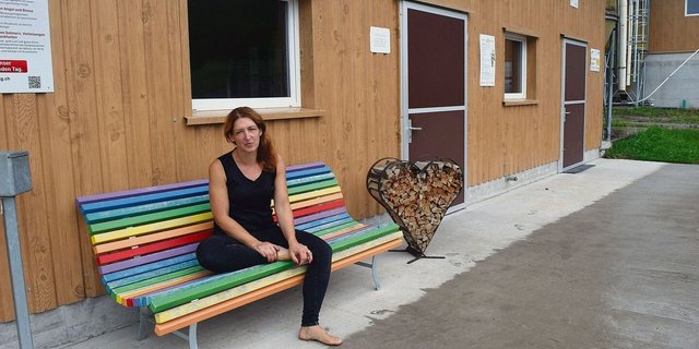 Beate Städler vor dem Hühnerstall, wo Kunden Eier in Selbstbedienung kaufen können. Die farbenfrohe Bank und die Herz-Dekoration verkörpern ein Stück weit ihren Charakter.