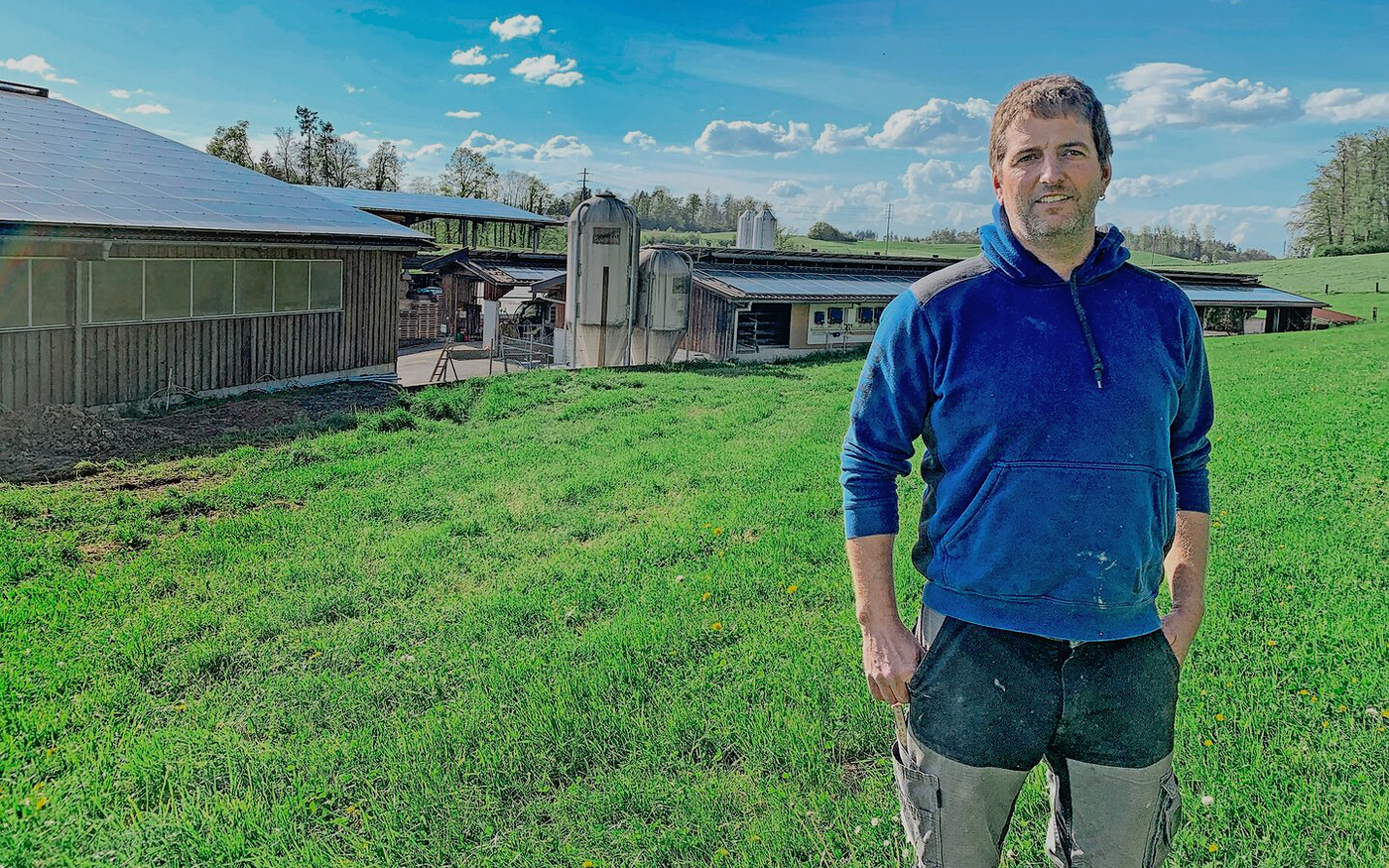  Philipp Boss von der Büelweid in Knonau vor den Gebäuden mit PV-Anlagen. Links die Maschinenhalle, rechts die Milchviehscheune, hinten die überdachten Fahrsilos. Nicht sichtbar ist die ebenfalls mit PV-Modulen belegte Geflügelmasthalle. 