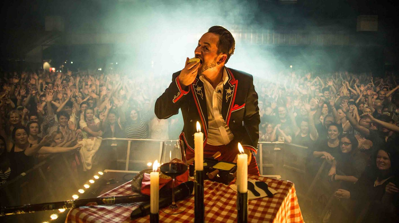 Raclette kann man auch auf der Bühne zubereiten und essen: Trauffer macht es vor. (Bild Raclette Suisse)