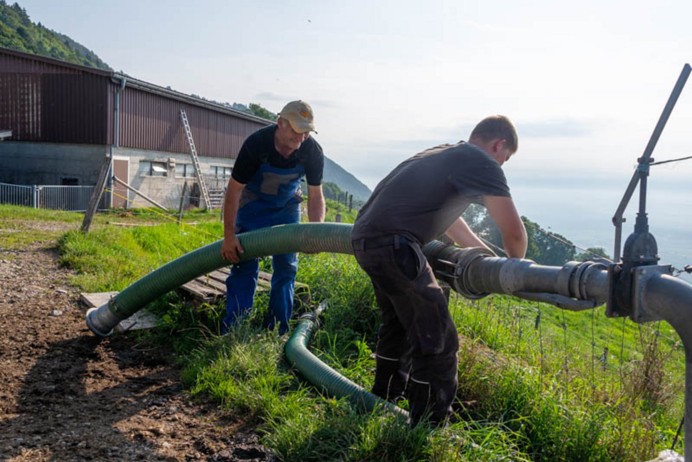 Ueli Fahrni (l) und Lehrling Jonas Zbinden bereiten die Gülleentnahme vor. Der Landwirt  nutzt einen Schleppschlauch für die Gülleausbringung rund um den Hof.  Für weiter entfernte gelegene Parzellen mietet er ein Druckfass zu.