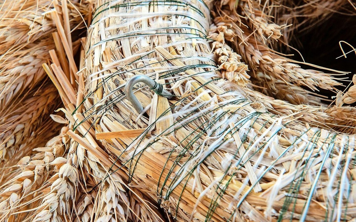 Das Ende des Drahtes wird um eine Agraffe oder einen dicken, gebogenen Draht gewickelt und satt angezogen in den Kranz gesteckt.