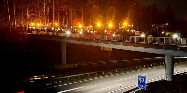 Traktoren mit Rundumleuchten über der Autobahn A6.