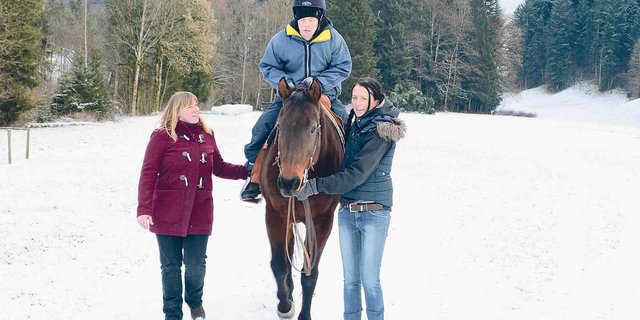 Michaela Schnyder (rechts) führt ihre Quarter Horse-Stute Olena und unterstützt gleichzeitig André bei der Reittherapie. Seine Begleitperson Luzia Wangeler hilft auf der anderen Seite. (Bild Andrea Gysin)