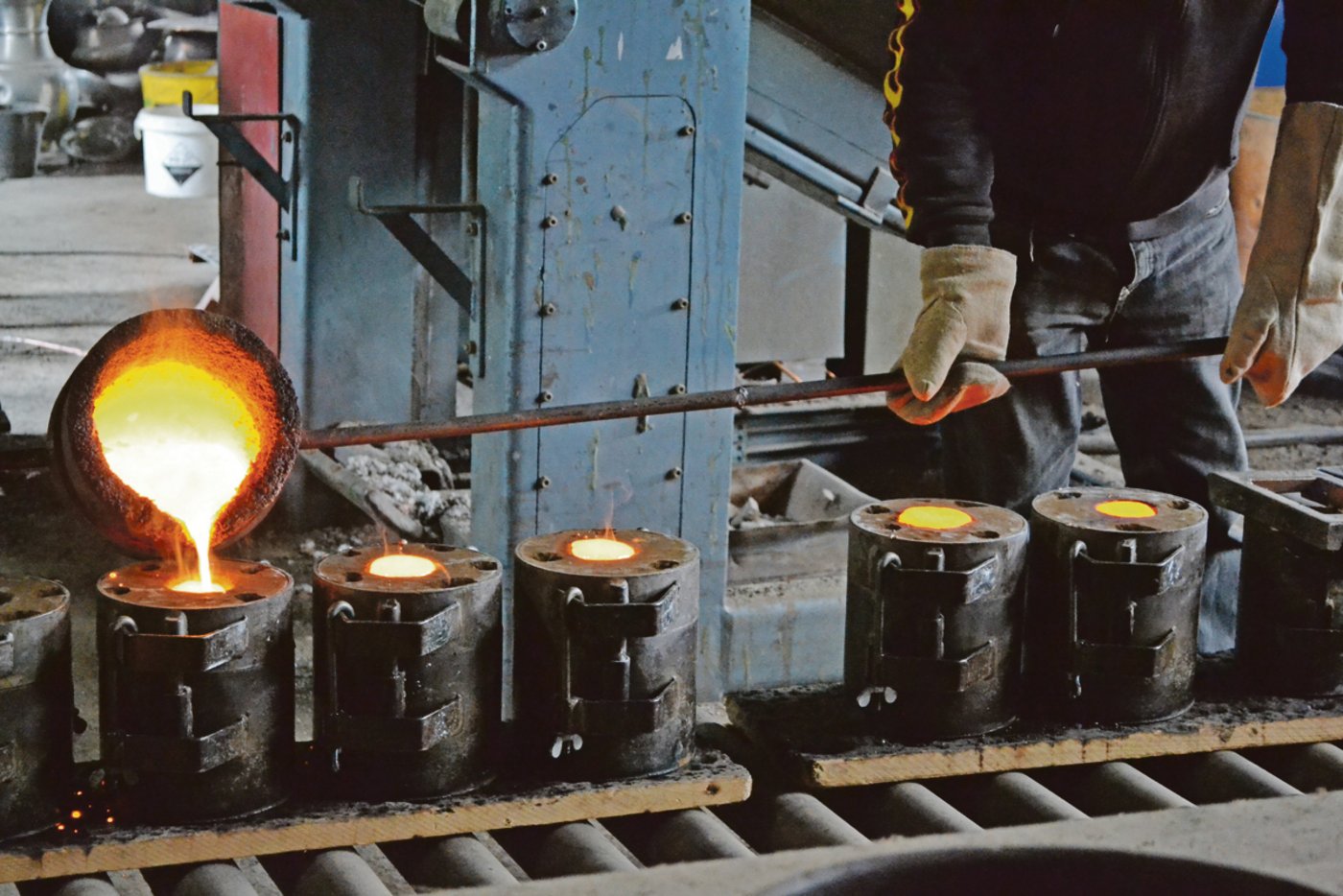 Die Legierung aus geschmolzenem Kupfer und Zinn wird vorsichtig in die vorbereiteten Formkästen eingegossen. 