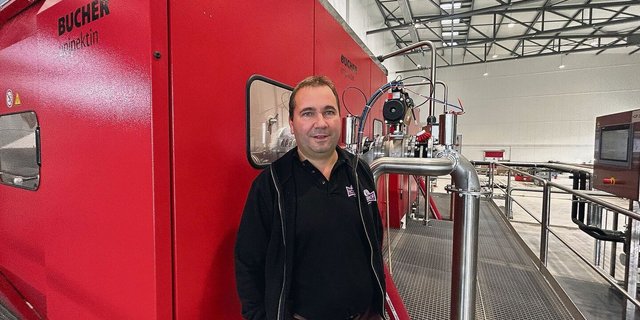 Christof Schenk, Inhaber und Geschäftsführer der Holderhof Produkt AG, zeigt, wie die Verarbeitung in der neuen Mosterei funktioniert. Im Hintergrund eine der beiden Bucherpressen. 