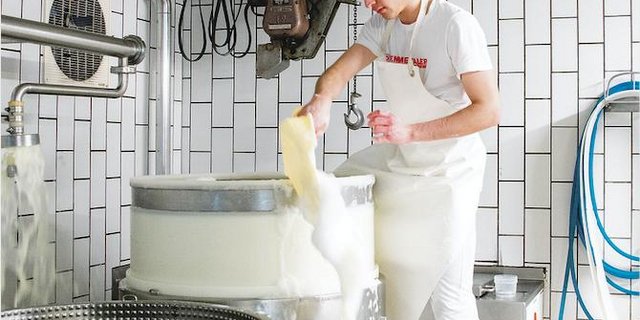 Claudio Macaluso schöpft in der Käserei in Tägertschi BE Molkeschaum aus der Käsepresse. (Bild hja)