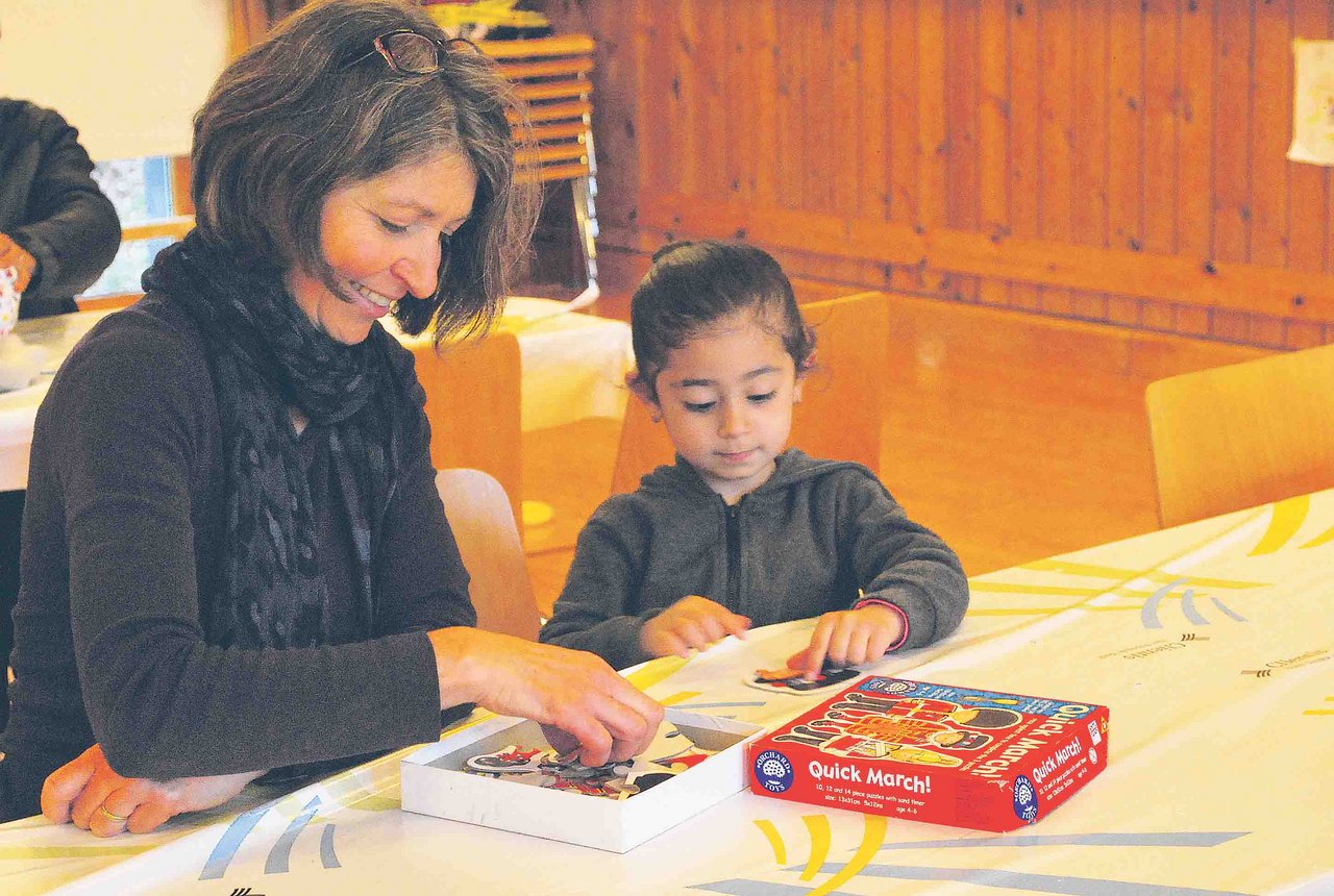 Eine Landfrau spielt mit einem Flüchtlingskind: Im Gemeinde-Mehrzweckraum konnten gemütliche Stunden verbracht werden. So rückten Krieg und Flucht kurz in den Hintergrund. (Bilder S. Gasser)