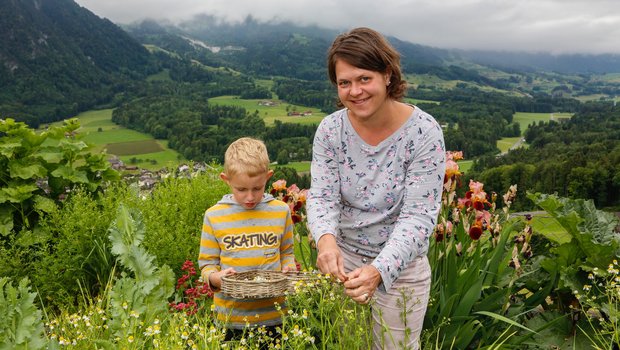 So geht das Kräuterpflücken einfacher: Sohn Manuel hält seinem Mami Helene Matter den Korb beim Pflücken der Kamillen für die Kräuterteemischung. (Bild Erika Rebsamen)