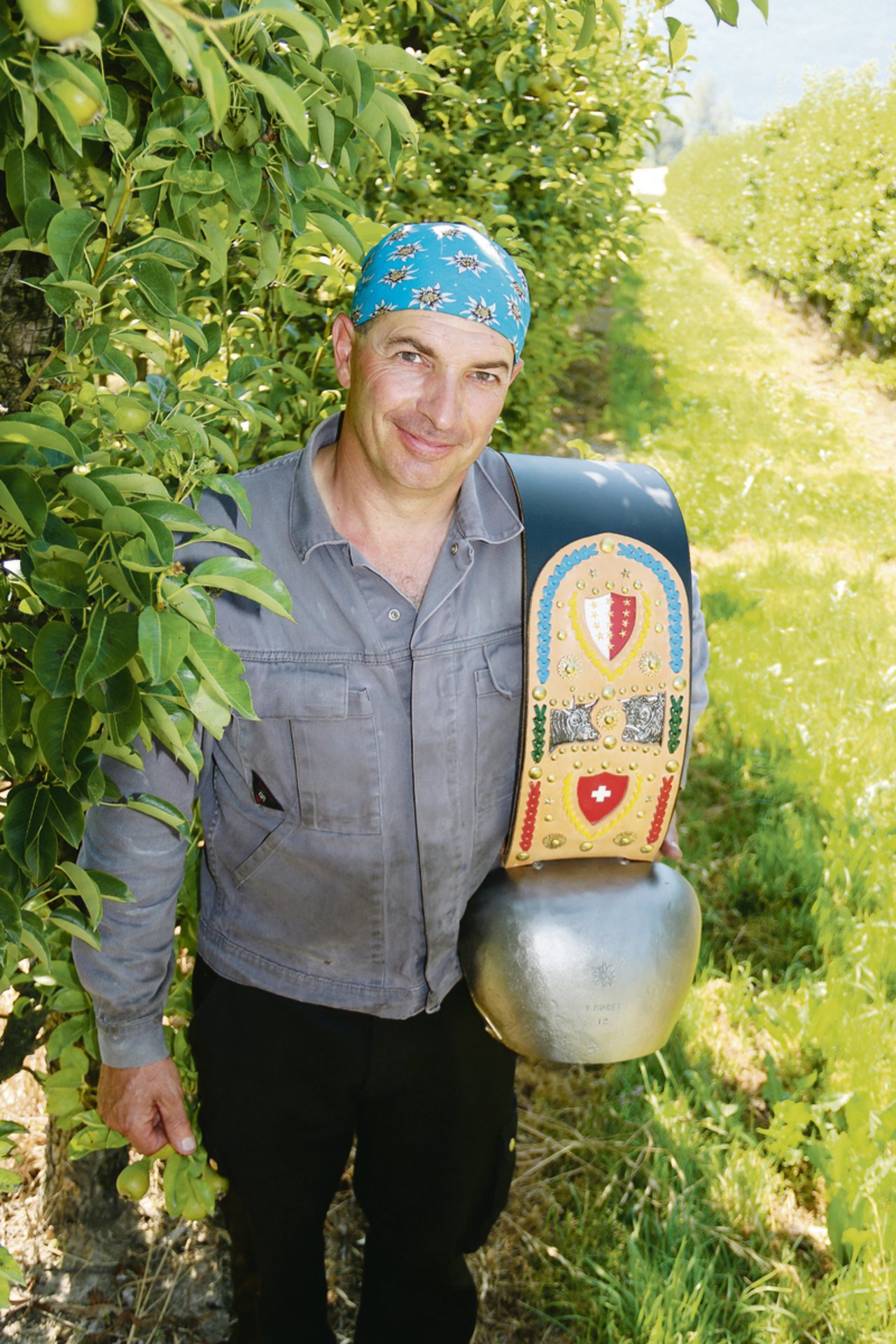 Yan Morets Schmiedewerkstatt liegt mitten in Walliser Aprikosen- und Apfelanlagen. Stolz präsentiert er eine Treichel, der handgefertigte Glockenriemen stammt von einem Geschäftspartner.