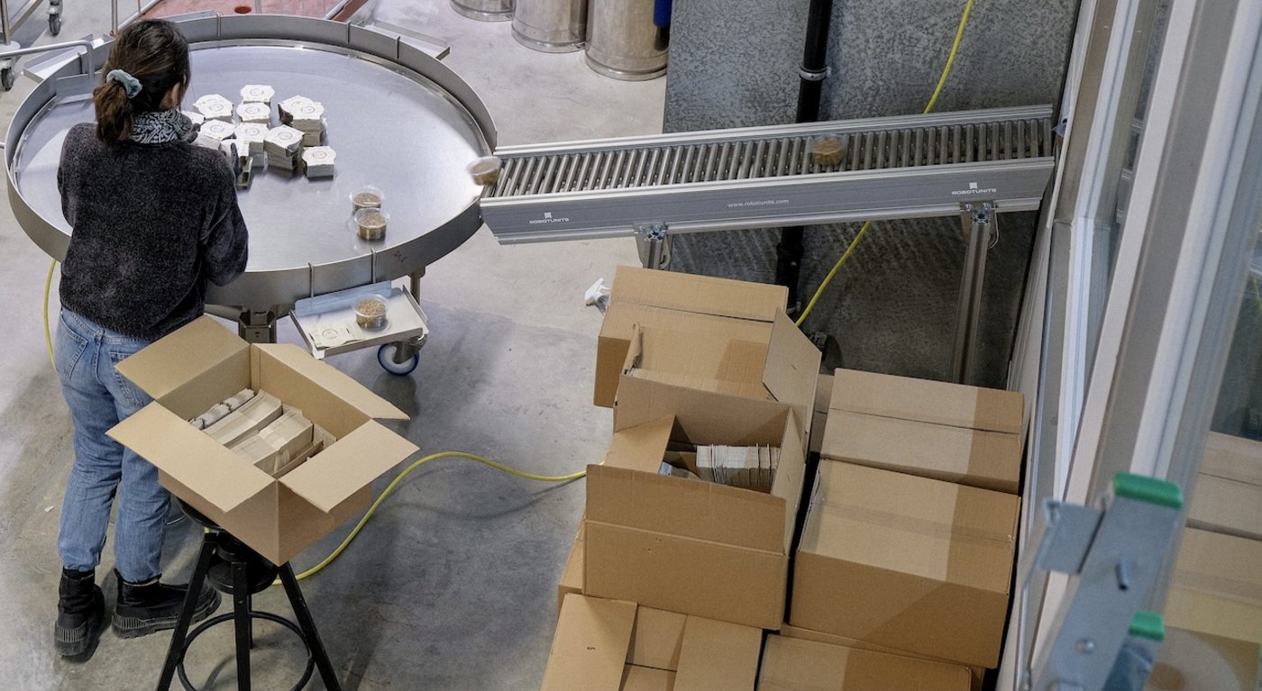 Über ein Förderband kommen die Produkte zum Etikettieren, (Bild New Roots)