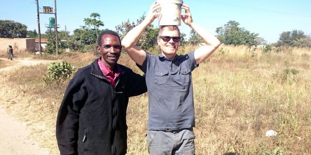 Der „Headman“ (so etwas wie ein traditioneller Gemeindepräsident) und der „Muzungu“ (Bezeichnung für einen Weissen) in Mphango. Ich übe mich im Milchkesseltragen auf dem Kopf, kann aber den sambischen Frauen nicht annähernd das Wasser reichen. (Bilder Markus Schär/zVg)