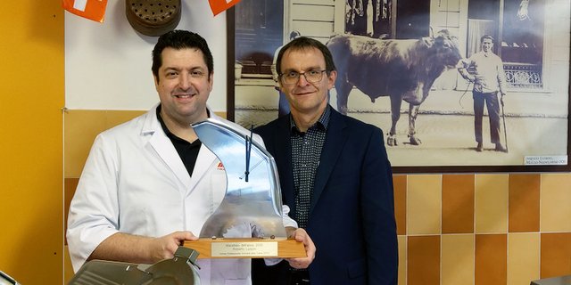 Roberto Luisoni präsentiert mit Stolz seinen Pokal, einer aus einem Blitzmesser gefertigten Uhr. Übergeben wurde ihm die Auzeichnung von Ruedi Hadorn, Direktor des Schweizer Fleisch-Fachverbands. (Hinweis: Die Masken wurden unter Einhaltung des Schutzkonzepts nur kurzzeitig für die Aufnahme abgenommen.) (Bild SFF)