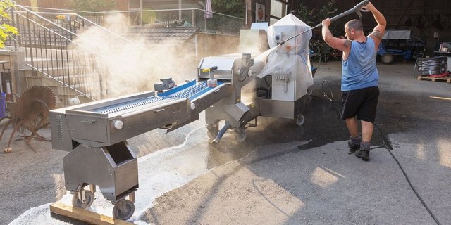 Serge Duperrex wäscht die Spargel-Sortiermaschine, bevor sie in der Remise eingelagert wird.