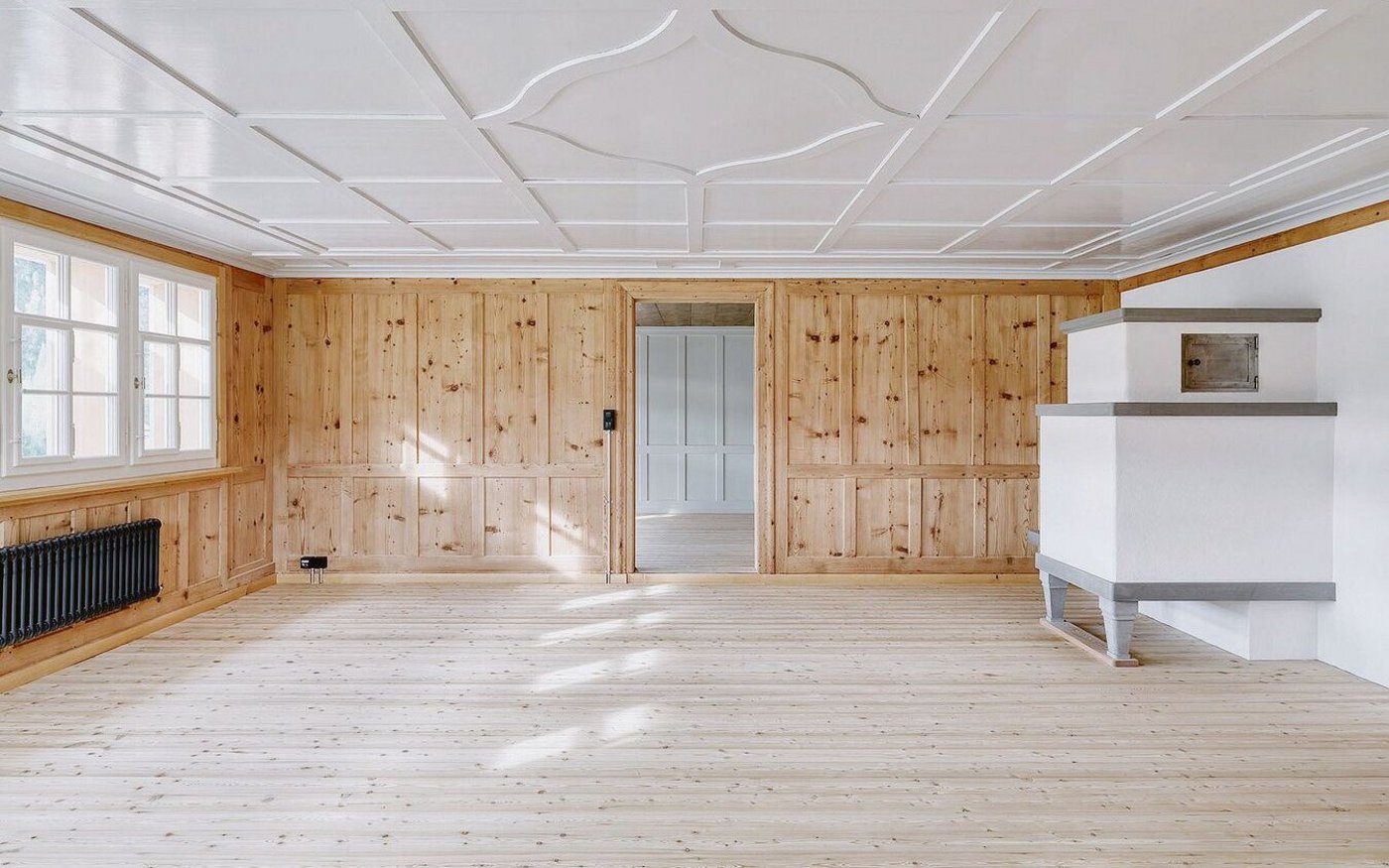 In der Stube setzen dezente, traditionelle Farbtöne einen Kontrast zu den Holzoberflächen in den restlichen Räumen.