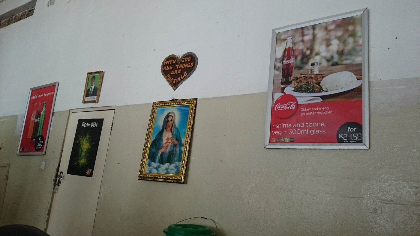 Nicht nur im Dünger- und Saatgutbereich infiltriert die Moderne die  Tradition in Sambia. Coca Cola und Nshima passen scheints wunderbar  zusammen: "Coke and meals go better together." Die Aufnahme stammt aus  einem kleinen Restaurant in Mazabuka, Southern Province.