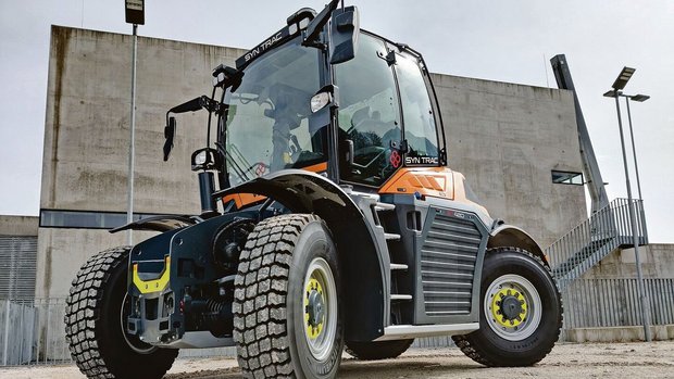 Der Syn-Trac des gle Der Syn-Trac des gleichnamigen österreichischen Herstellers kann dank seines Schnellwechselsystems in Windeseile verschiedenste Anbaugeräte ankoppeln, ohne dass der Fahrer die Kabine verlassen muss.