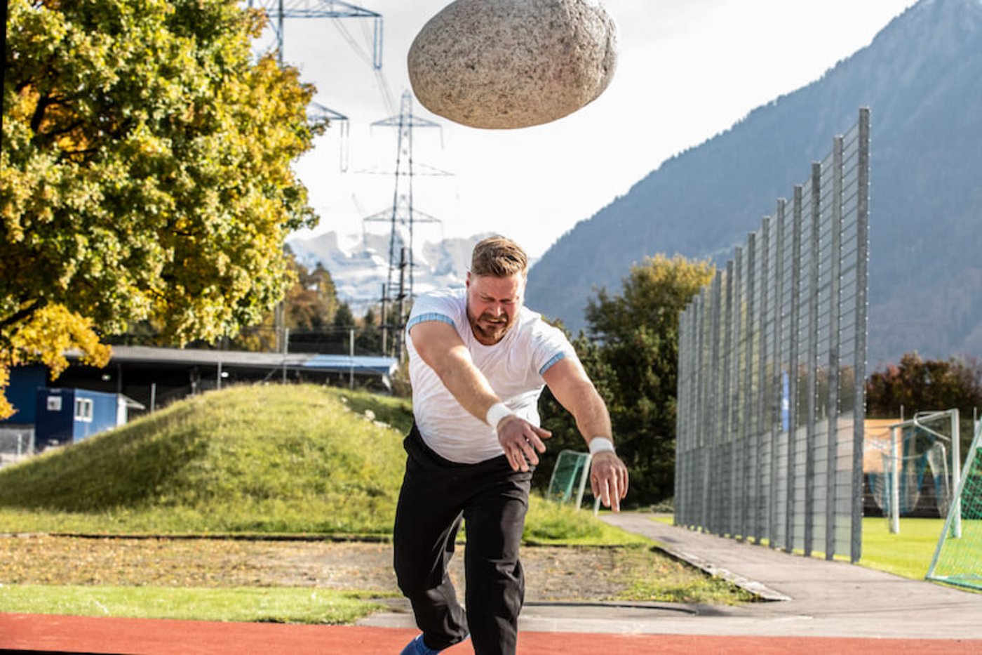 Nach einem Anlauf wirft der Steinstosser den Stein ab in den Sand. Er landet bei 3,85 Metern.