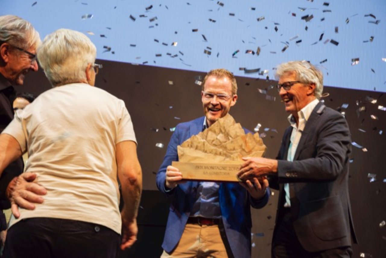 Die Gewinner des Prix Montagne 2018: La Conditoria aus Sedrun/GR. Reto Schmid, Inhaber der Conditoria, nimmt von Jury-Präsident Bernhard Russi den Preis entgegen. (Bild Schweizer Berghilfe)