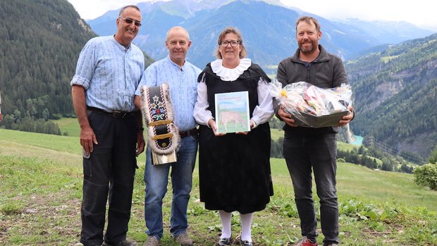 Als Anerkennung ihrer Leistung wurden Toni (mit Glocke) und Nicole Sigron (mit Bio Bruna Award) von Marco Parpan (l.) Lucas Margreth (r.) mit einem Früchtekorb beschenkt. (Bild vcd)