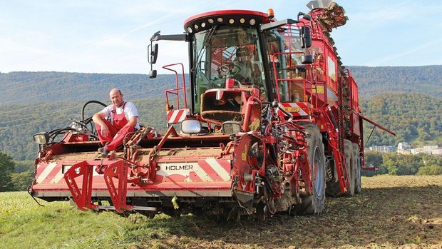 Holmer: Rübenernte-Maschine Hans-Peter Burri sitzt auf dem Balken des RübenerntersRüben