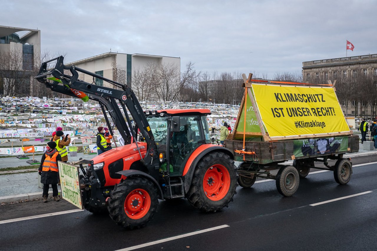 Bauern zeigten ihre Unterstützung mit Traktoren und sorgten für etwas Landluft in der Hauptstadt. Dieses Plakat bezieht sich auf die Klage dreier deutscher Bio-Bauern gegen die Bundesregierung, weil ihre Existenz durch den Klimawandel bedroht wird. 
