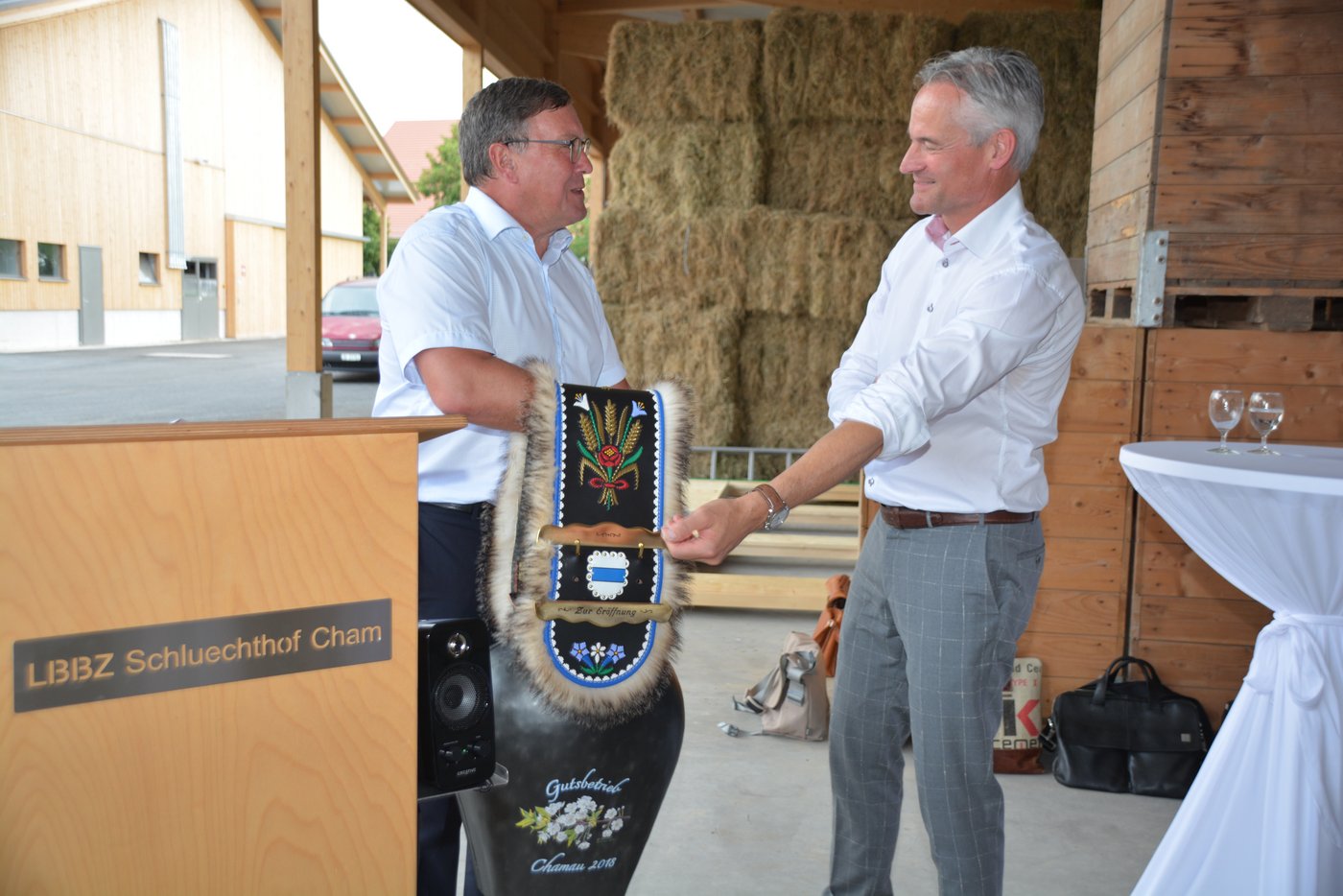 Bereit für dïe Übergabe: Der Zuger Baudirekter Urs Hürlimann übergibt an Volkswirtschaftsdirektor Matthias Michel (r) symbolisch eine Treichel, und damit auch den neuen Gutsbetrieb Chamau.
