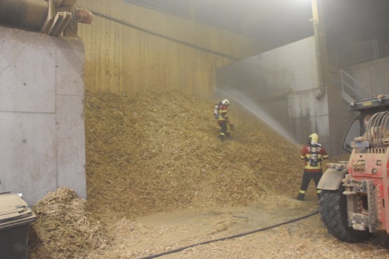 Feuerwehrleute bekämpfen den Mottbrand im Holzschnitzellager. (Bilder Kapo GR)