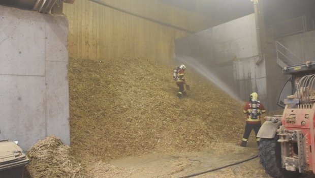 Feuerwehrleute bekämpfen den Mottbrand im Holzschnitzellager. (Bilder Kapo GR)