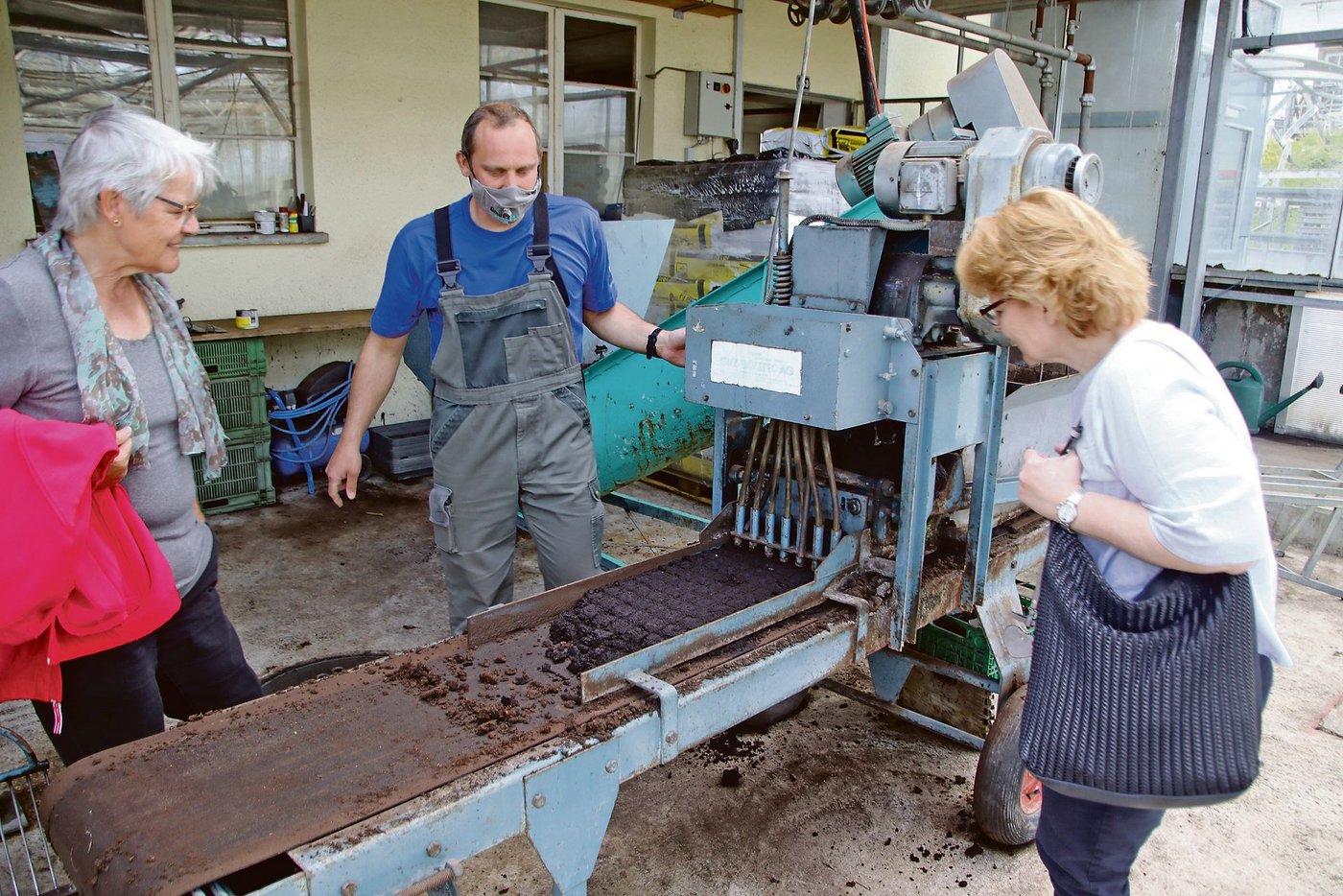 In einer alten Maschine werden die Pflanztöpfchen gepresst. In jedes Töpfchen wird ein Samenkorn abgelegt.