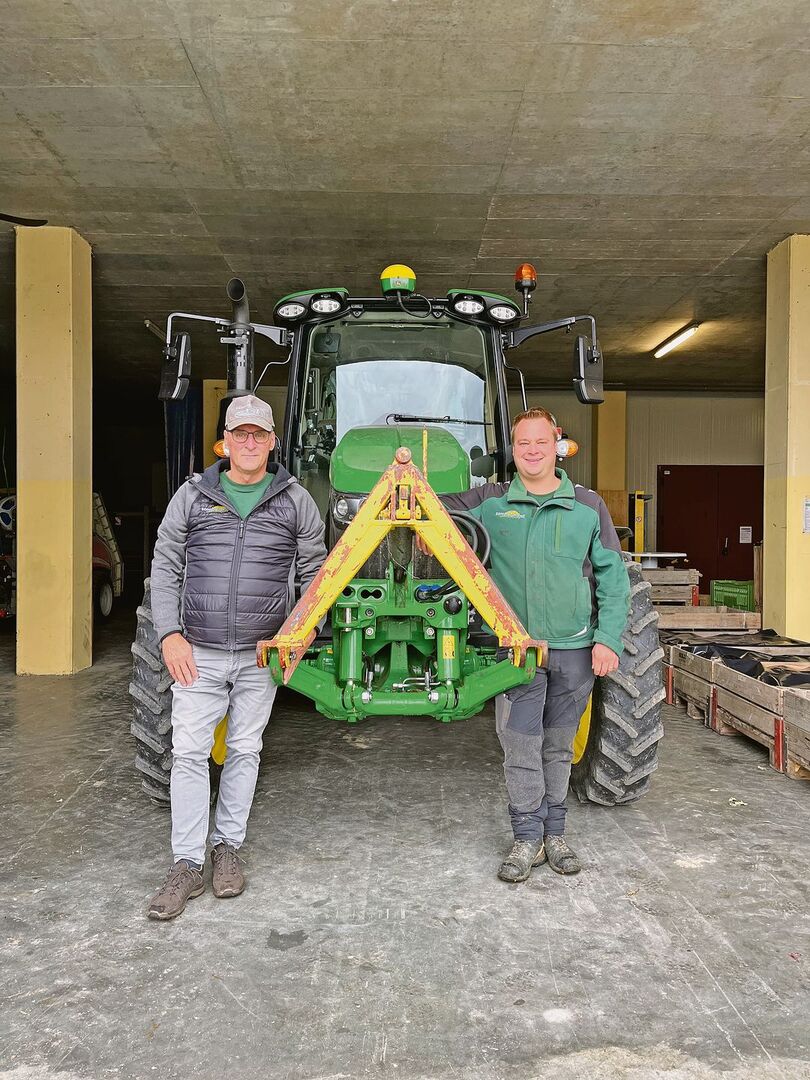 Thomas (links) und Marc Grüter stehen vor einem ihrer John Deere-Traktoren.