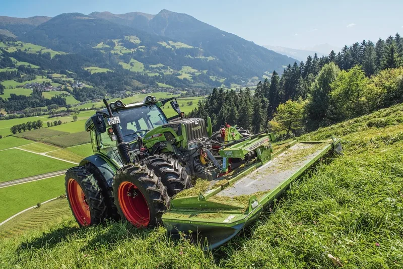 Der Fendt 211 Vario Traktor bei Mähen im Berggebiet.