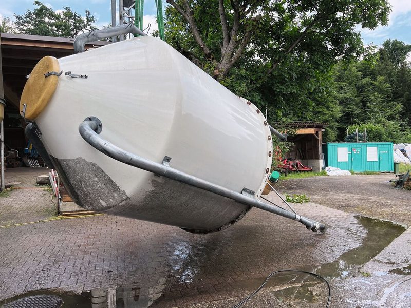 Das weisse Futtersilo liegt umgekippt am Boden, um gewaschen zu werden.