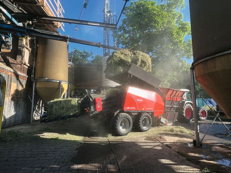 Eine Ballenpresse presst loses Heu aus dem Heustock zu Ballen.