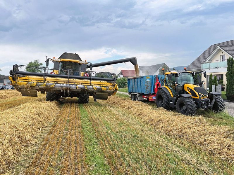 Der Mähdrescher leitet die geerntete Gerste in den Wagen, der nebenher, vom Traktor gezogen, fährt.