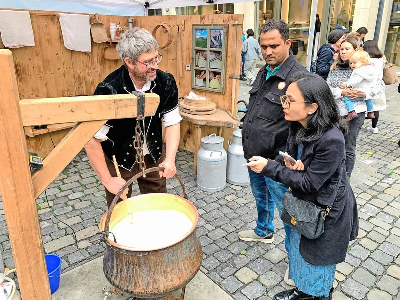 Landwirt Stefan Sieber aus dem Berner Oberland (l.) erklärt Touristen in Luzern die Herstellung von Käse.