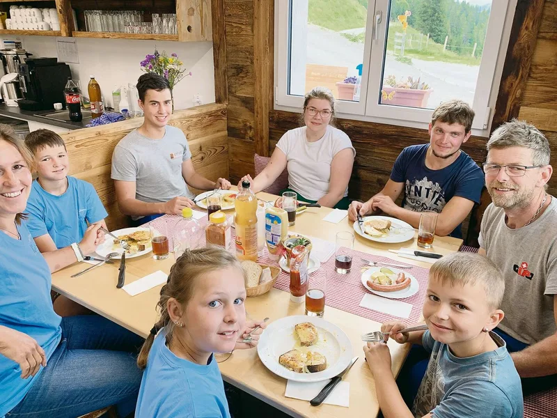 Mittagspause im Chäsi-Beizli: Käserin Emma Sinkkonen (Mitte, weisses Shirt) mit den Älplern Adrian Arnold (rechts von Emma), Beat Arnold (rechts von Adrian) und weiteren Helferinnen und Helfern.