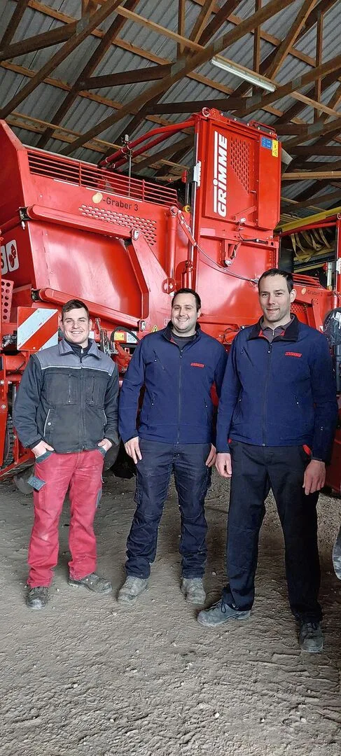 Christian Mollet, Stefan Wyss und Daniel Wyss stehen vor einem roten Kartoffelernter.