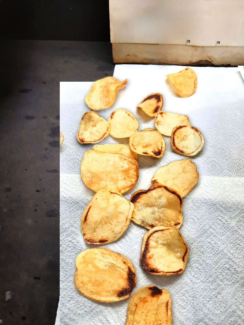 Gebackene Kartoffeln liegen auf einem Haushaltspapier. Sie zeigen deutlich braune Stellen.