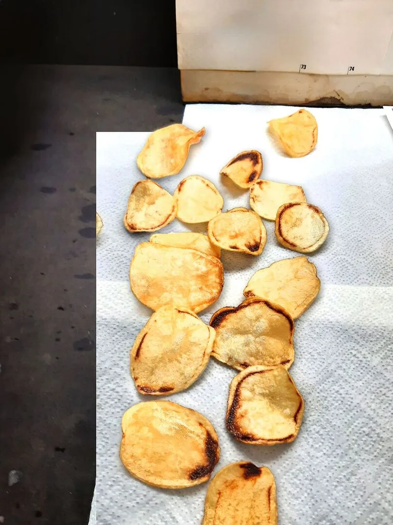 Gebackene Kartoffeln liegen auf einem Haushaltspapier. Sie zeigen deutlich braune Stellen.