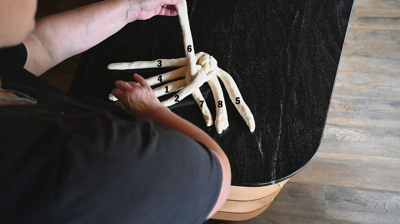 Mit linker Hand unter rechtem Arm durchgreifen und Strang 6 holen, kreuzen. Rechte Hand legt Strang 2 neben Strang 1 ab.