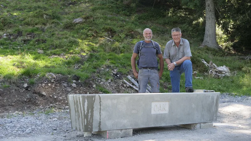Paul Bellmont (links) und Karl Betschar stehen am fertig gestellten Tränkebrunnen auf der Alp.