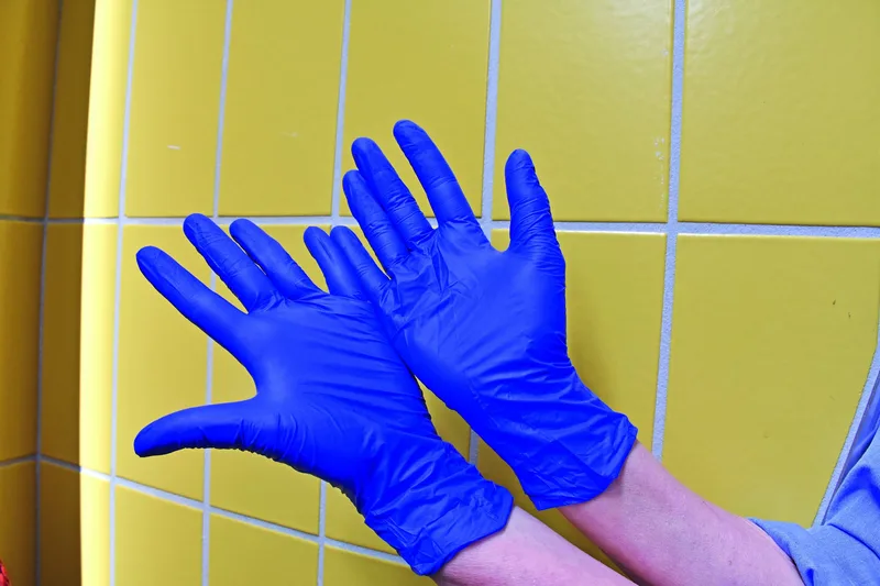 Zwei Hände mit blauen Hygiene-Handschuhen