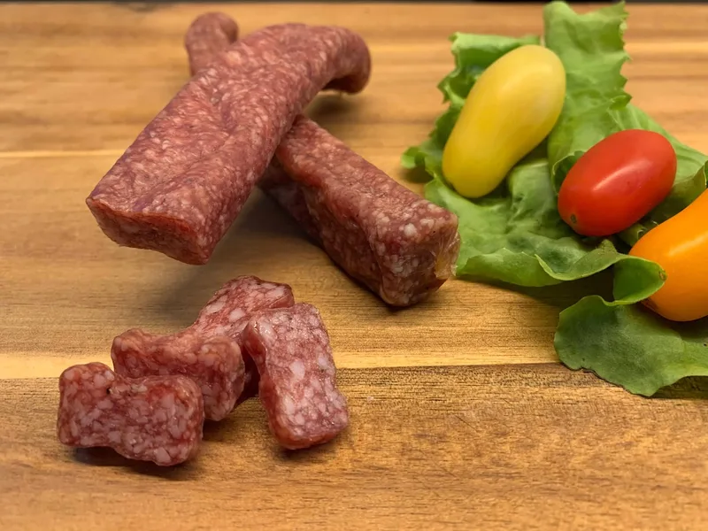 Ein Landjäger aus Hennenfleisch liegt auf dem Tisch und wurde bereits angeschnitten.