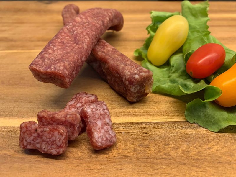 Ein Landjäger aus Hennenfleisch liegt auf dem Tisch und wurde bereits angeschnitten.