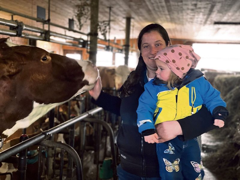Im Anbindestall stehen Swiss-Fleckvieh-Kühe. Doris Friedli (hier mit der zweijährigen Tochter Kerstin) hilft auf dem Hof, wo es sie braucht.