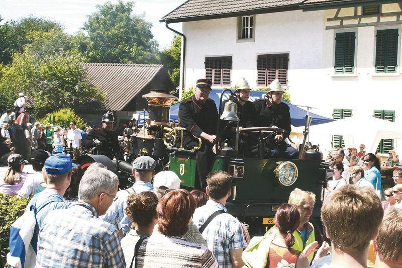 Unzählige Besucher(innen) säumen den Strassenrand während des Corsos: Ein altes Feuerwehrmobil fährt vorbei.