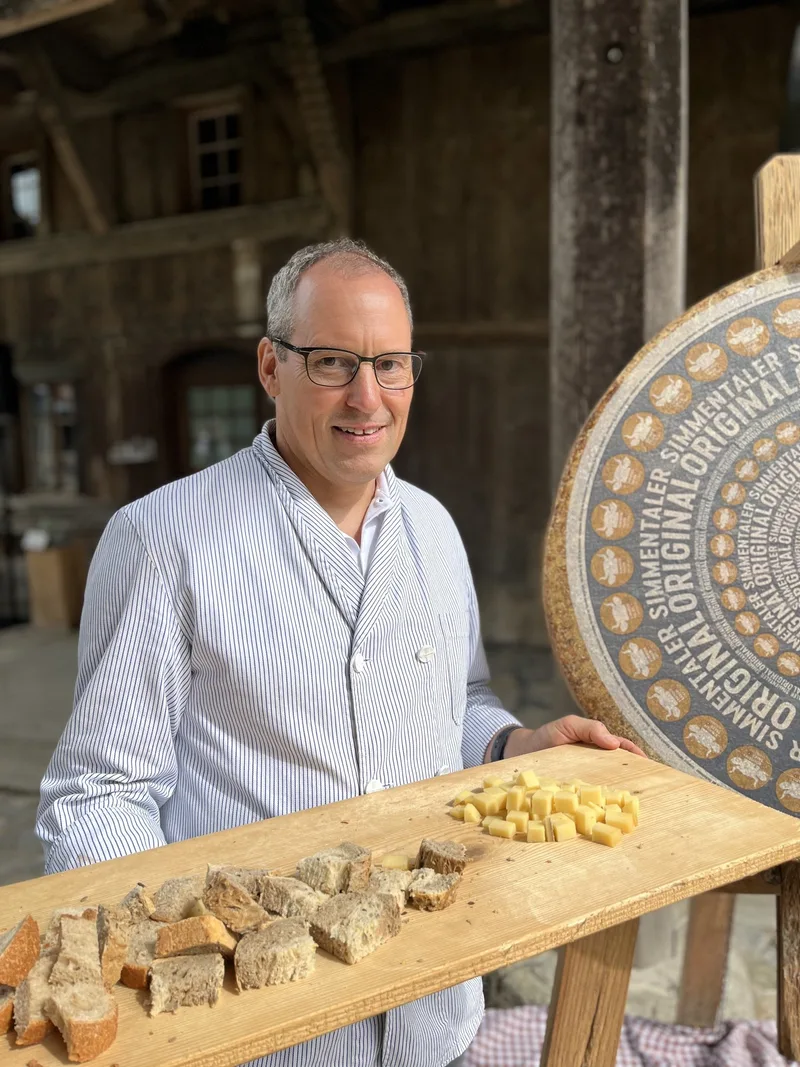 Jakob Siegenthaler steht mit angeschnittenem Käse vor der Etikette des "Simmentaler Originals".