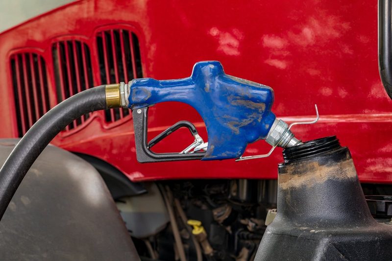 Diesel fuel nozzle fueling farm tractor. Farming input costs, fu