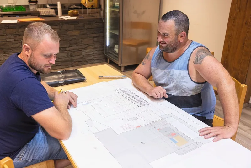 Philipp Etterli, Planer bei der Firma Moser Stalleinrichtungen, bespricht mit Serge Duperrex die Pläne für den erweiterten Milchviehstall mit Biogas-Anlage.